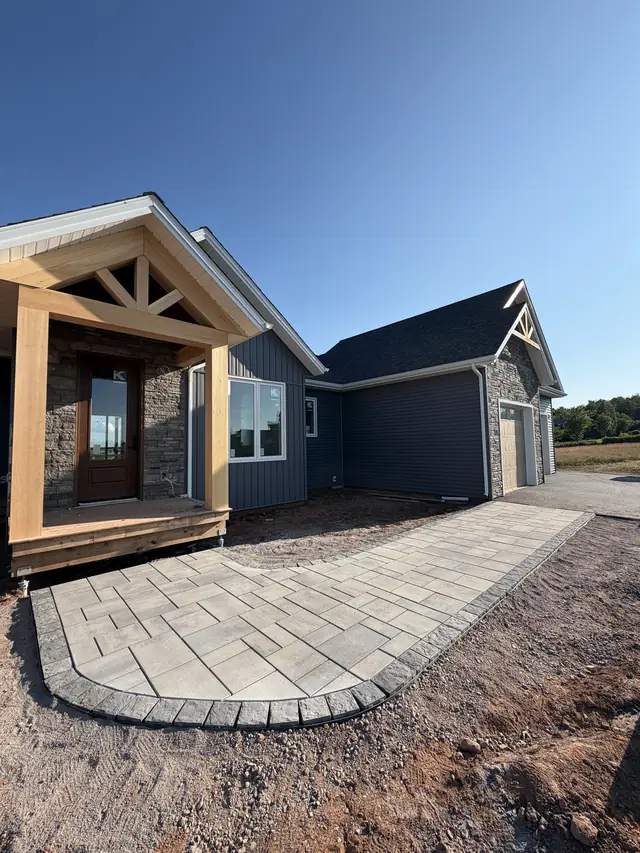 Curved paver walkway with charcoal border leading to a timber-frame front entry