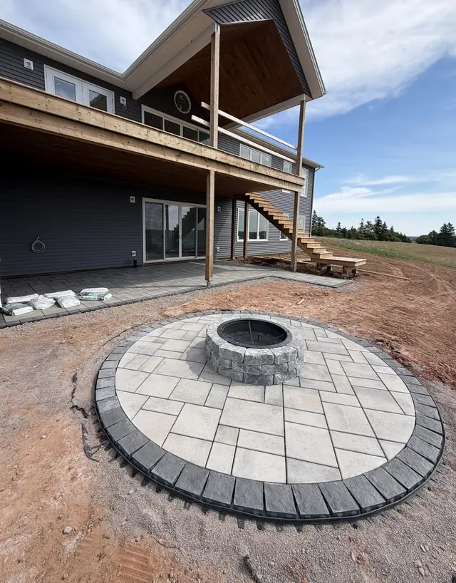 Circular paver fire-pit patio with a charcoal soldier-course border below a two-storey deck