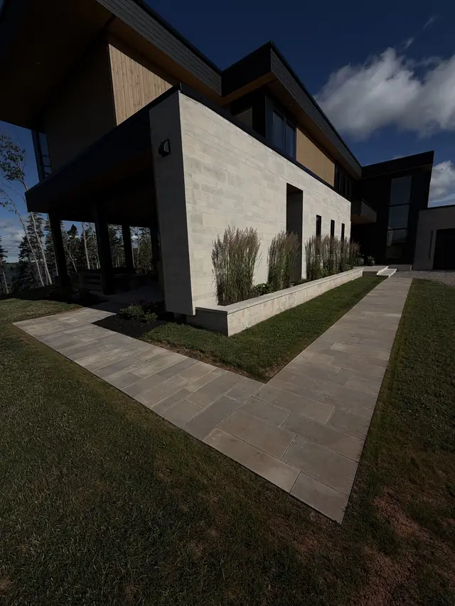 L-shaped large-format slab walkway and raised planter wall at a modern PEI home